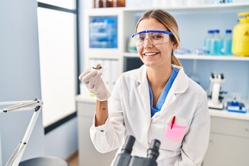 Young hispanic woman scientist looking sample at laboratory