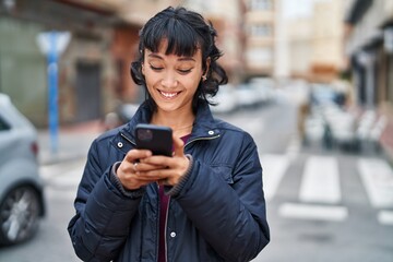 Young beautiful hispanic woman smiling confident using smartphone at street