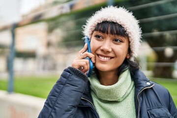 Young beautiful hispanic woman smiling confident talking on smartphone at street