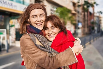 Two women mother and daughter hugging each other at street