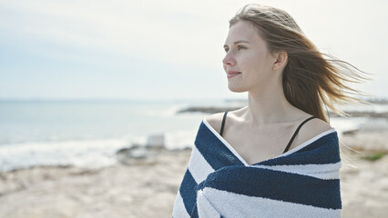 Young blonde woman tourist wearing bikini covering with towel at beach