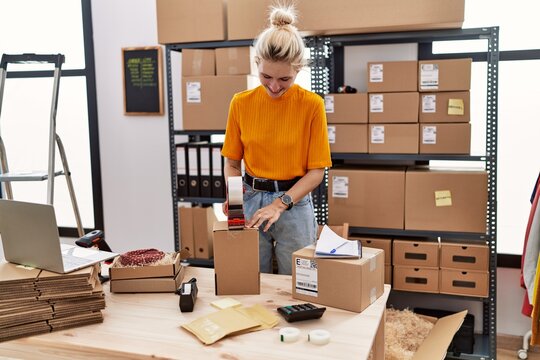 Young blonde woman ecommerce business worker packing cardboard box at office