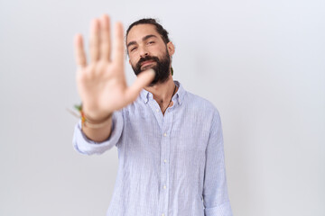 Hispanic man with beard wearing casual shirt doing stop sing with palm of the hand. warning...