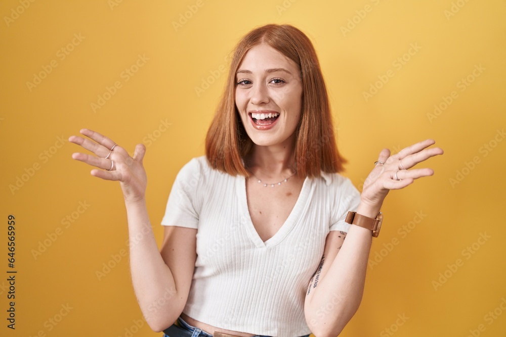 Poster young redhead woman standing over yellow background celebrating mad and crazy for success with arms 