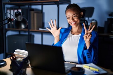 Beautiful african american woman working at the office at night showing and pointing up with fingers number eight while smiling confident and happy.