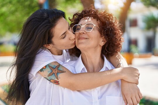 Two women mother and daughter hugging each other and kissing at park