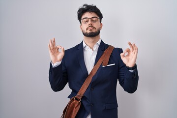 Hispanic man with beard wearing business clothes relaxed and smiling with eyes closed doing meditation gesture with fingers. yoga concept.
