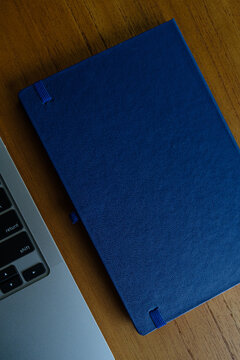 fotografia superior de bloco de notas azul com computador aberto ao lado com espaço livre para texto sem pessoas