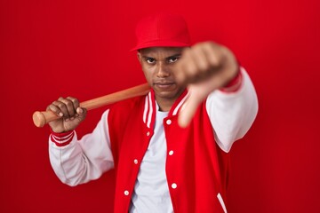 Young hispanic man playing baseball holding bat looking unhappy and angry showing rejection and negative with thumbs down gesture. bad expression.