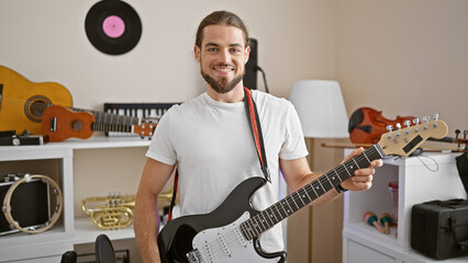 Young hispanic man musician smiling confident playing electrical guitar at music studio