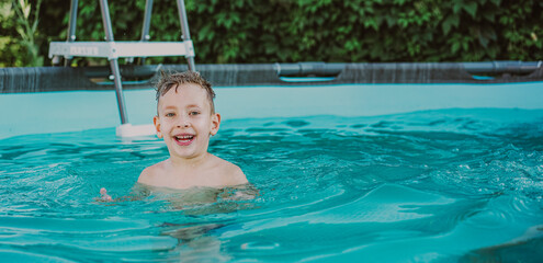 Naklejka premium Little boy swims in the pool at their summer cottage. Back yard vacations concept