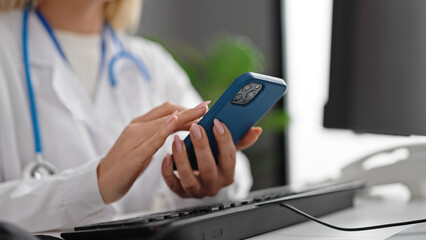 Young blonde woman doctor using smartphone working at clinic
