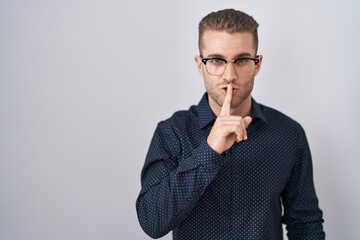Young caucasian man standing over isolated background asking to be quiet with finger on lips. silence and secret concept.