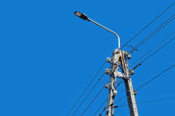 Power supply background. High voltage pole with lamp isolated on blue sky. High street lamp. High...