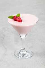 Raspberry cream jelly, Panna Cotta in a martini glass. Light gray background. Close up