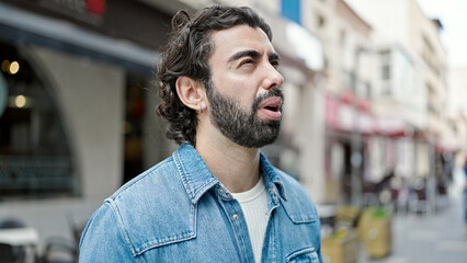 Young hispanic man looking to the side with serious expression at street