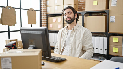 Young hispanic man ecommerce business worker using computer sitting on table at office