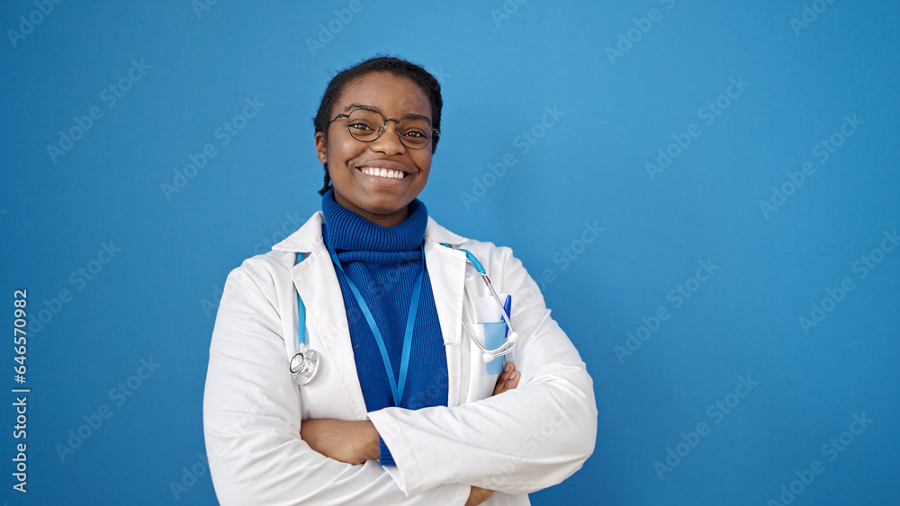 Wall mural African american woman doctor smiling confident standing with arms crossed gesture over isolated blue background