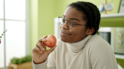African american woman smiling confident holding apple at dinning room