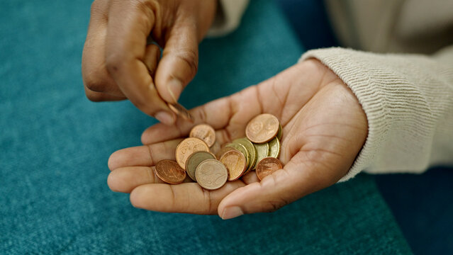 African American Woman Holding Coins In The Hand At Dinning Room