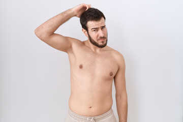 Fototapeta premium Young hispanic man standing shirtless over white background confuse and wonder about question. uncertain with doubt, thinking with hand on head. pensive concept.