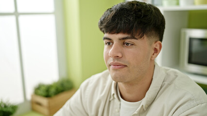 Young hispanic man sitting on table with relaxed expression at dinning room