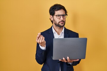 Handsome latin man working using computer laptop doing money gesture with hands, asking for salary...