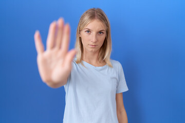 Fototapeta premium Young caucasian woman wearing casual blue t shirt doing stop sing with palm of the hand. warning expression with negative and serious gesture on the face.