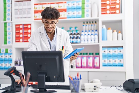 Young Arab Man Pharmacist Using Computer And Touchpad At Pharmacy