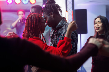 Young couple in love dancing together and hugging in crowded nightclub. African american man and...