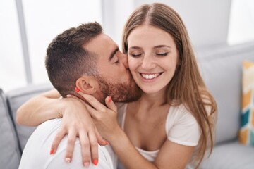 Obraz na płótnie Canvas Man and woman couple sitting on sofa kissing at home