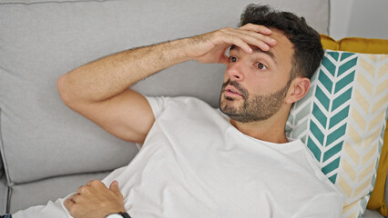 Obraz premium Young hispanic man suffering for headache lying on sofa at home