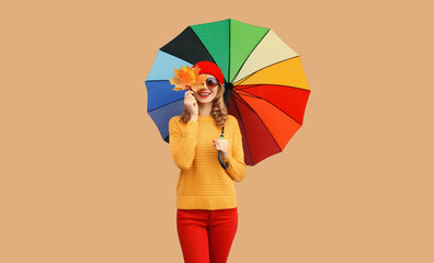 Autumn color style outfit, stylish cheerful young woman holds yellow maple leaves with colorful...