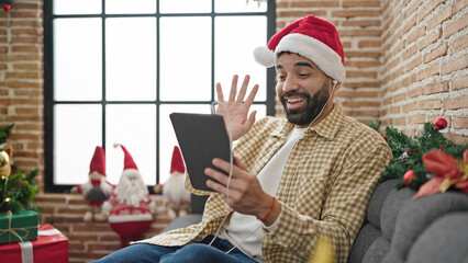 Young hispanic man celebrating christmas having video call at home