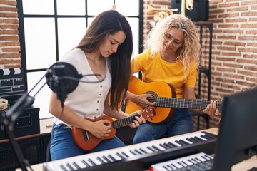Fototapeta na wymiar Two women musicians playing classical guitar and ukulele at music studio