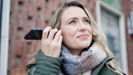 Young blonde woman listening to voice message at street