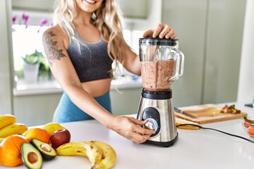 Young woman smiling confident blending healthy smoothie at kitchen