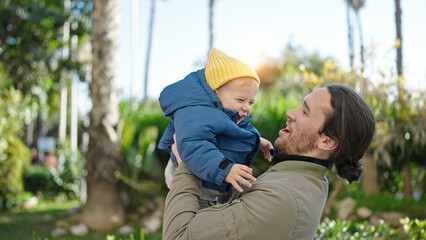 Father and son smiling confident hugging each other at park