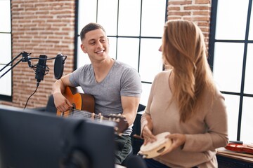 Man and woman musicians playing classical guitar and tambourine at music studio