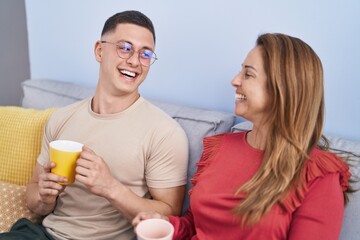 Man and woman mother and son drinking coffee sitting on sofa at home