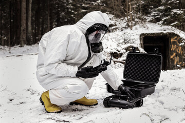 a man in a chemical suit with a GCS ground control station. robot for searching radiation sources