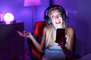 Young caucasian woman playing video games with smartphone celebrating achievement with happy smile and winner expression with raised hand