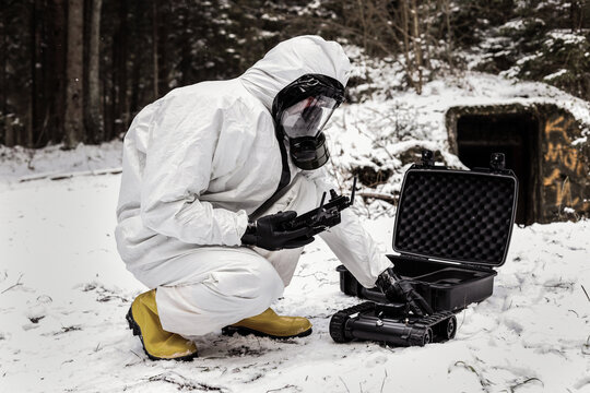 a man in a chemical suit with a GCS ground control station. robot for searching radiation sources