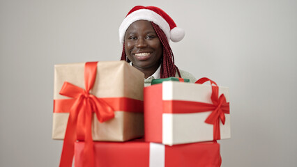 African woman with braided hair wearing christmas hat holding gifts over white background