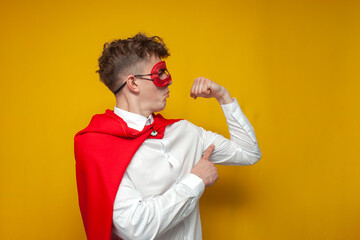 confident guy in a superhero costume shows the muscles on his arm, the concept of a strong man