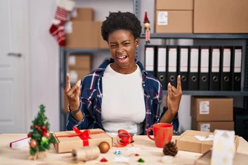 Papier Peint photo Magasin de musique African american woman working at small business doing christmas decoration shouting with crazy expression doing rock symbol with hands up. music star. heavy concept.