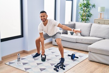 African american man smiling confident using kettlebell training at home