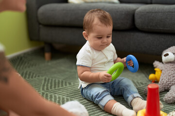 Fototapeta premium Adorable toddler playing with toys sitting on floor at home