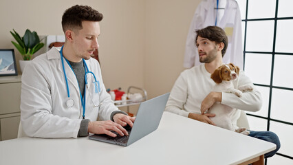 Two men having veterinarian consultation using laptop at veterinary clinic