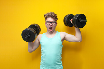 confident guy student lifts heavy dumbbells on a pink background, motivated nerd in glasses goes in...